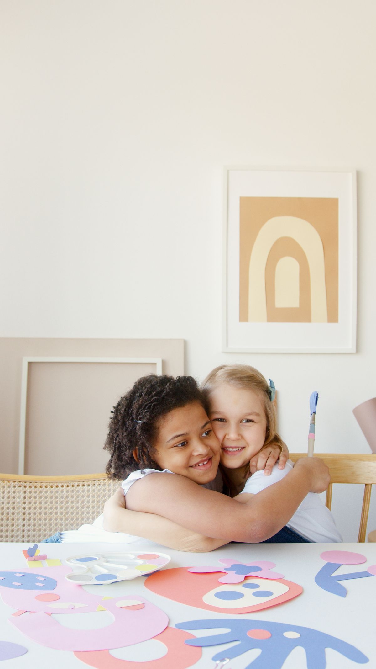 Deux enfants se prennent dans les bras pendant un atelier créatif.